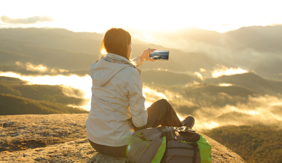 山頂でスマートフォンを使う登山者（docomo Starlink Directの利用イメージ）